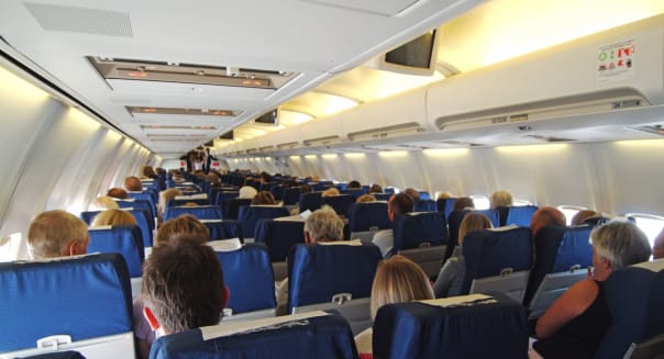 A68PNE Passengers on board holiday jet in flight seated three each side of gangway aisle