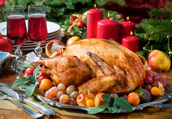 Roasted turkey on holiday table, candles and Christmas tree with ornaments