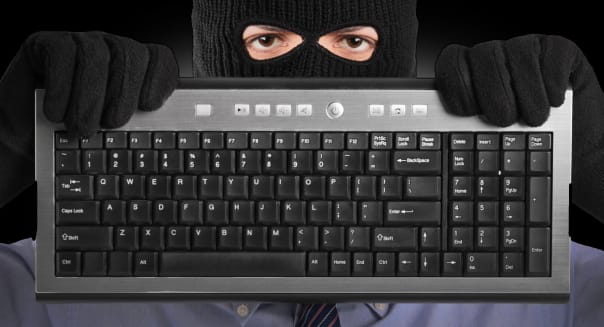 BYRP3Y A hacker with robbery mask holding a keyboard scam email scammer scammed computer scam adult; background; bandit; black;