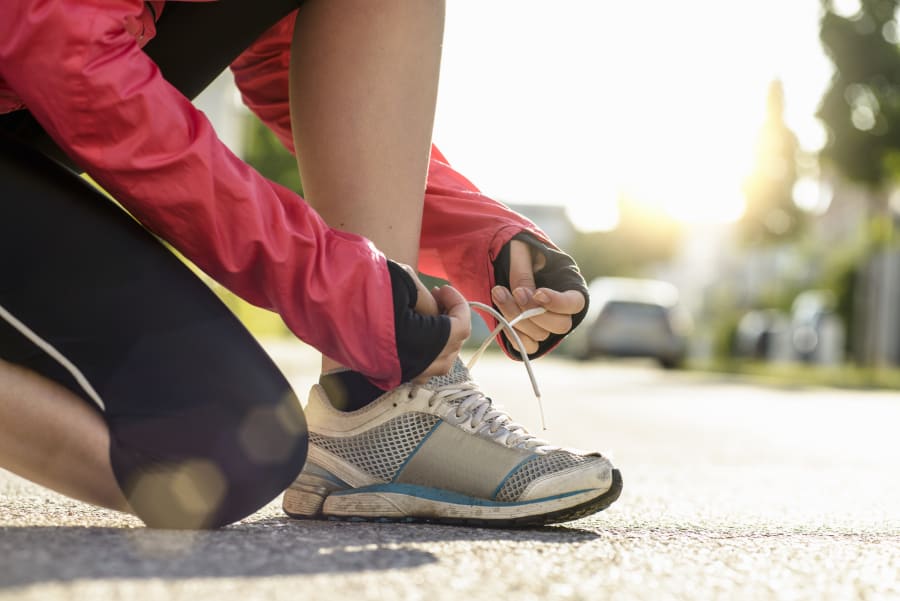 female runner tying shoe lace in a urban area