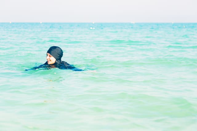 ... in burkini swimming in the sea, persian gulf, jumeirah beach in dubai