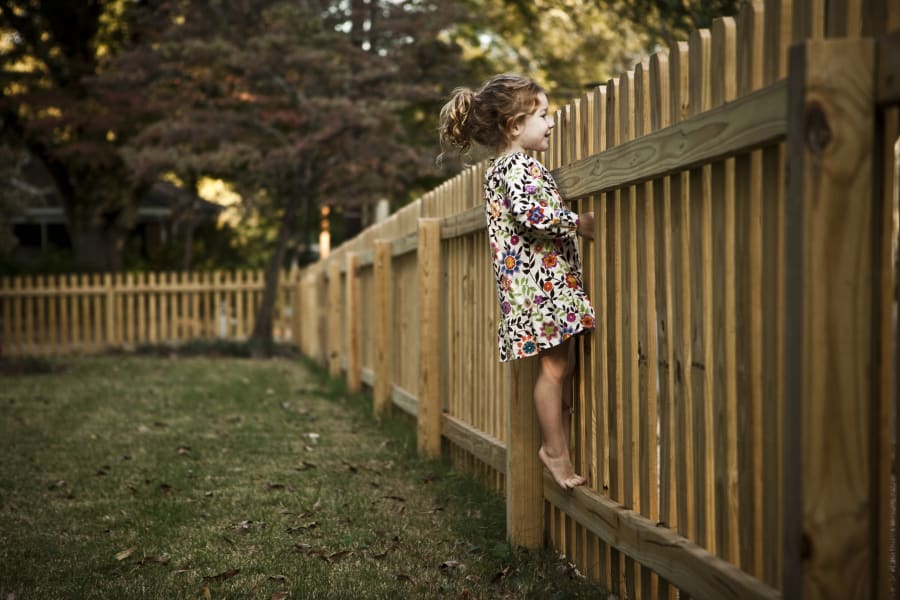 girl (4 yrs) peeking over fence