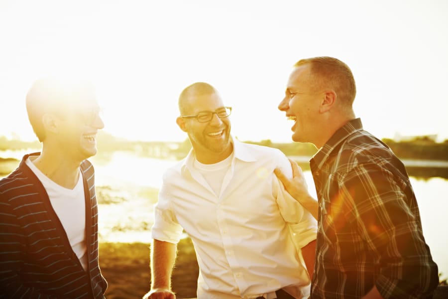 Gay couple in discussion with friend at sunset