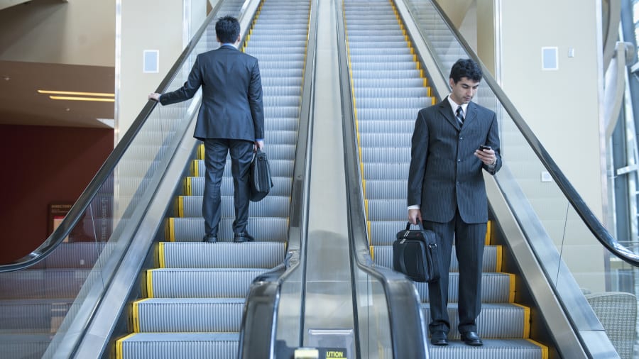 Businessmen standing on escalators