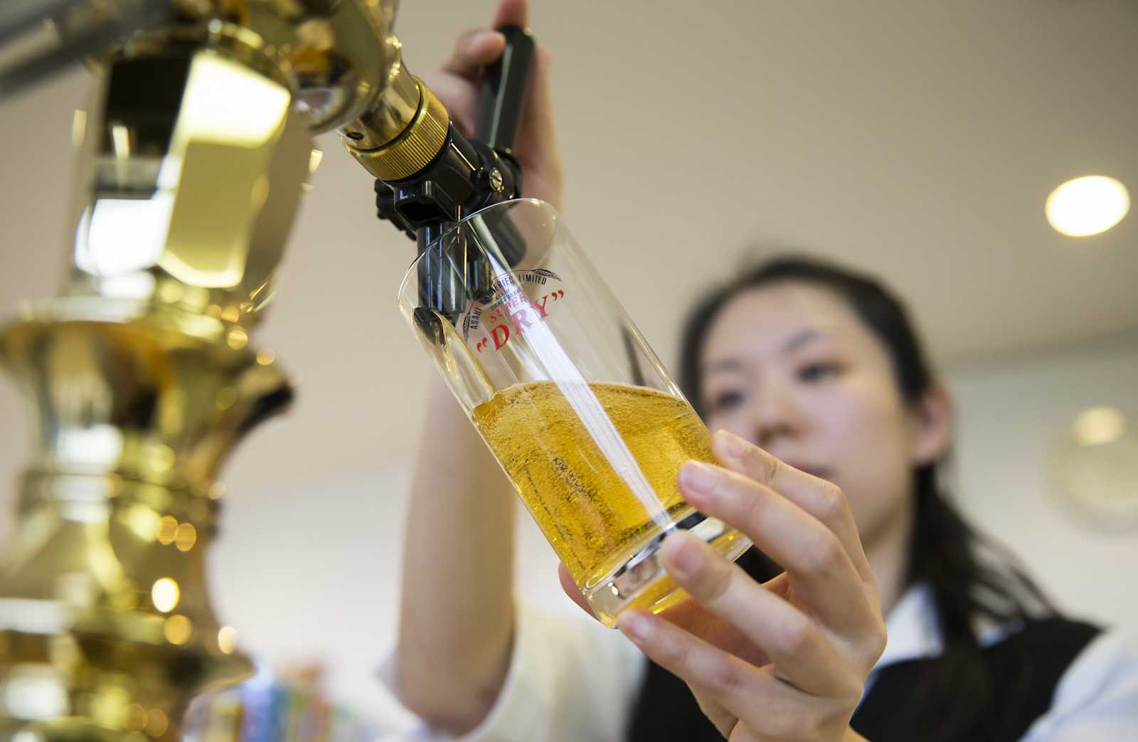 bartender-pours-a-glass-of-asahi-super-dry-beer-from-a-beer-tap-at-picture-id648902798