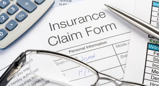 Handwritten Insurance Claim Form with pen and calculator