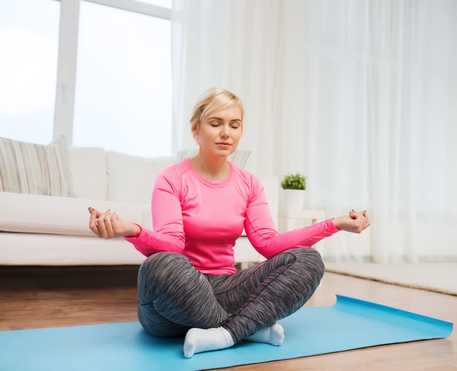 happy woman stretching leg on mat at home