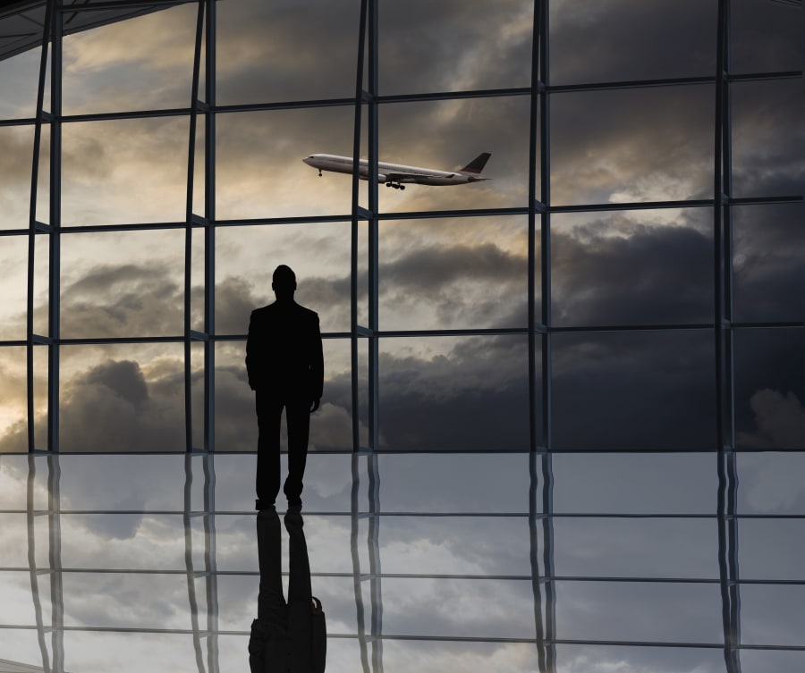 Mixed race businessman standing near window at airport