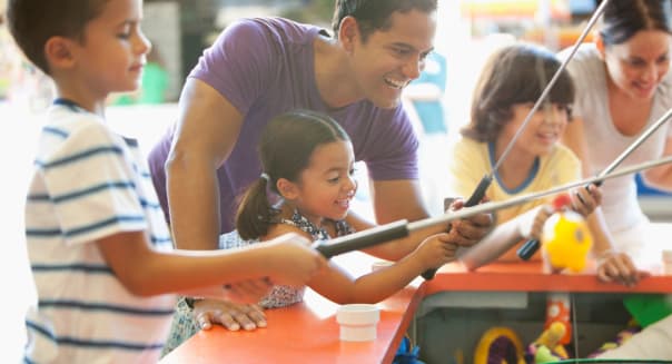 Hispanic family playing arcade game in amusement park
