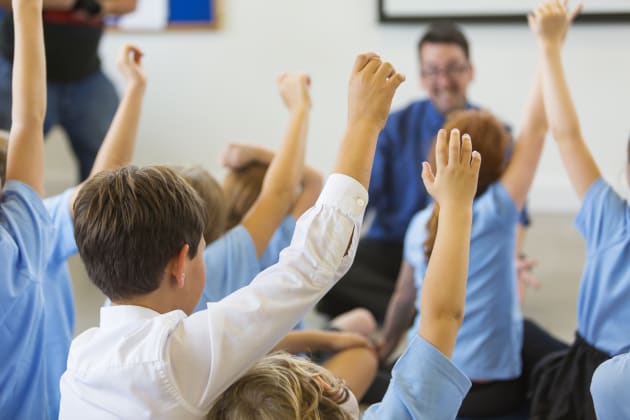 Excited School Children in Uniform with Hands Up