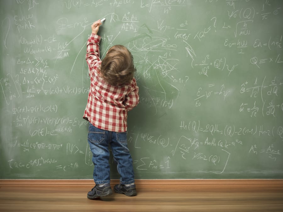 Little boy writing on green blackboard