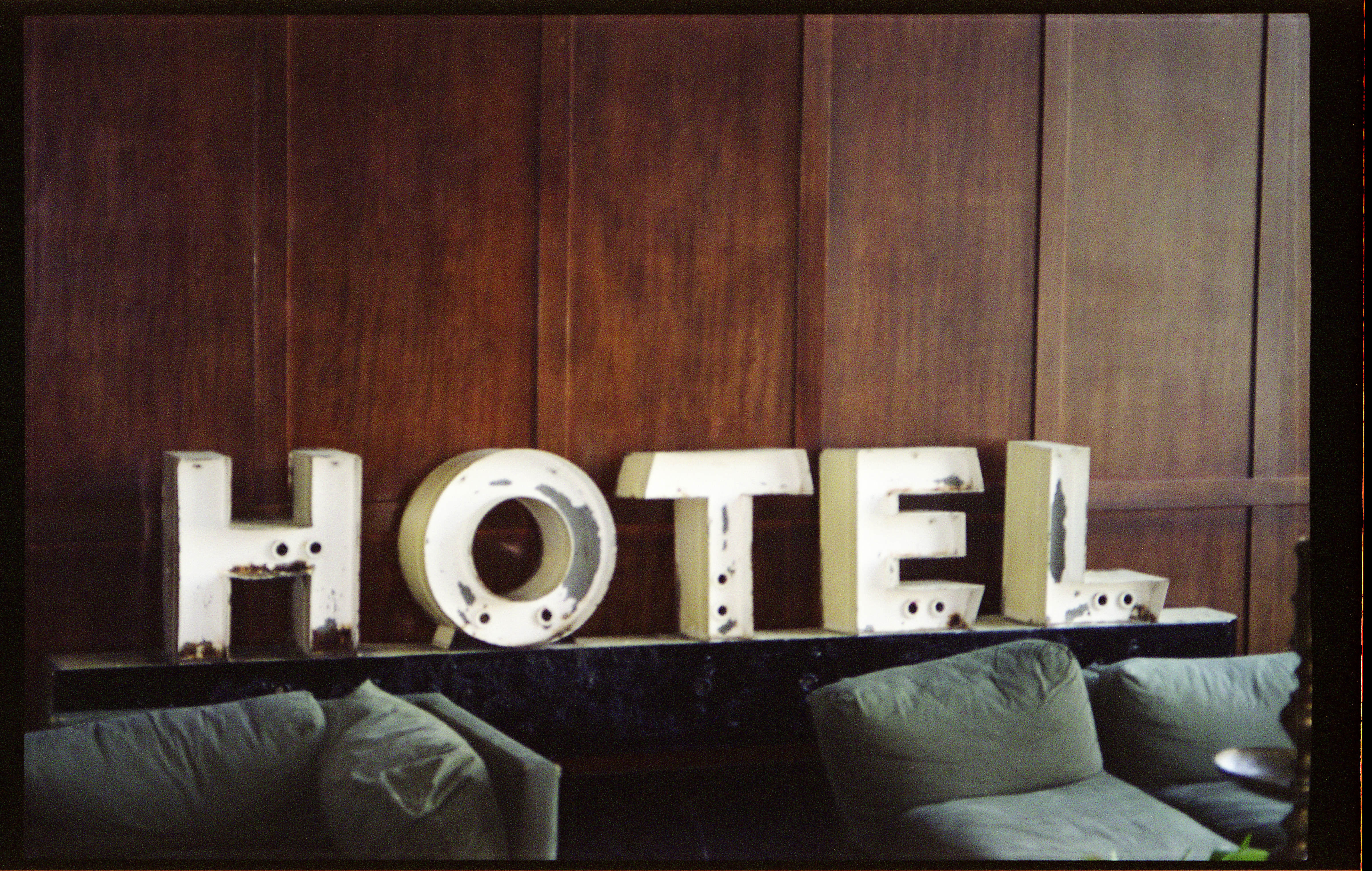 Vintage white 'HOTEL' sign leaning against dark wooden wall in lobby of ACE Hotel in Portland, Oregon.