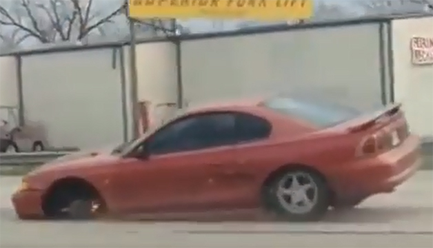 A motorist videos a Mustang driving down the highway on three wheels.