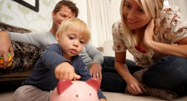 Father, mother and son putting coins in piggy bank