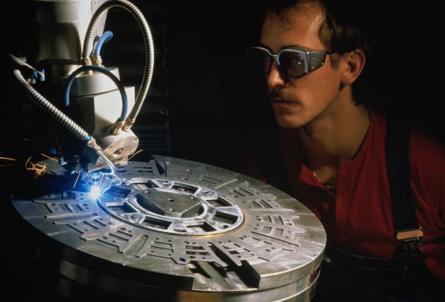 Worker watching clutch driving plate being welded by laser