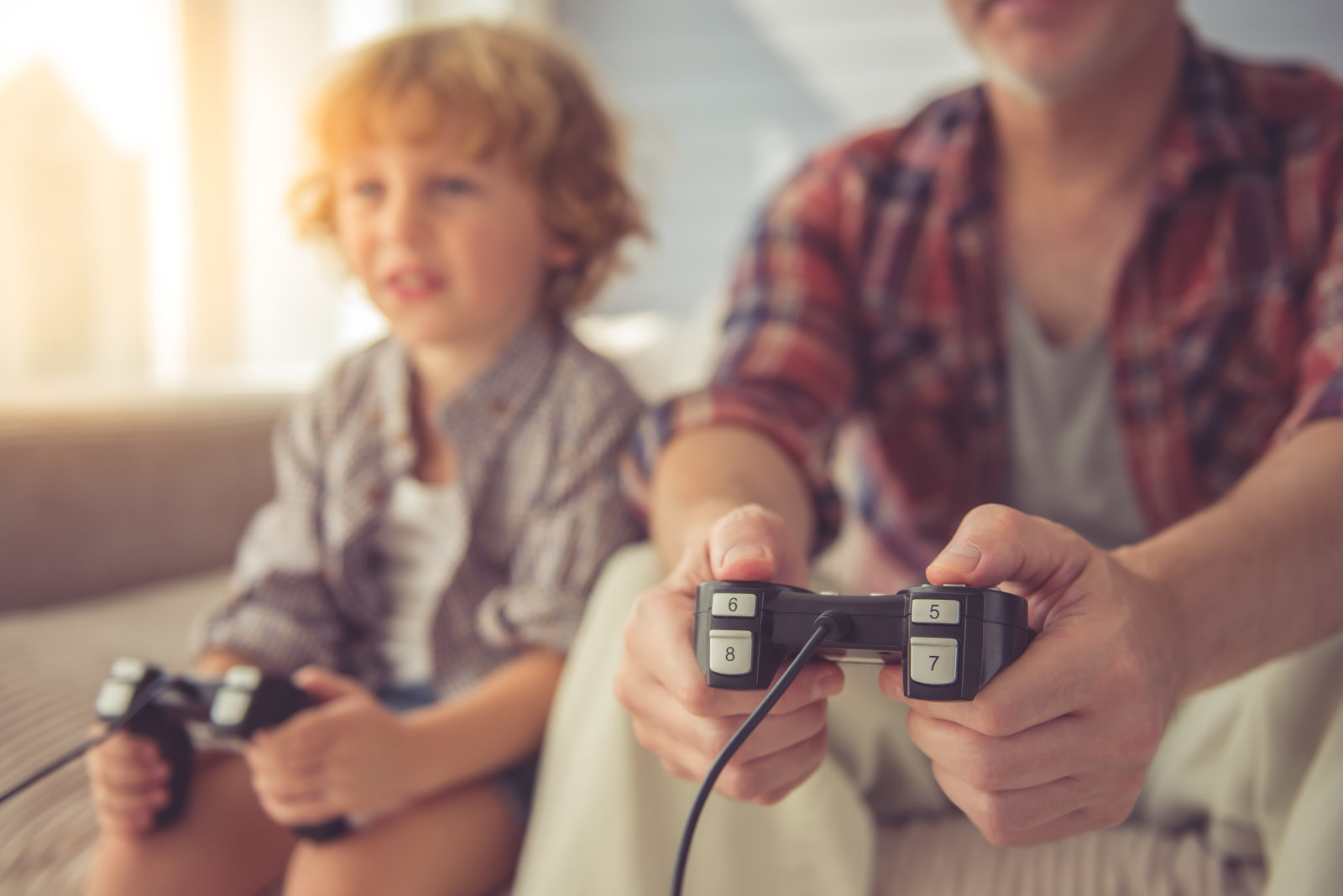 Cropped image of handsome grandpa and grandson playing game console while spending time together at home