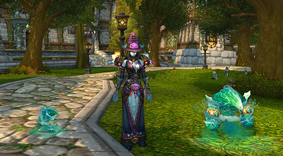 A draenei mage stands with two water elementals, one is very small and the other is a bit bigger.
