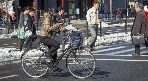 Japanese person checking a cellphone while on a bike