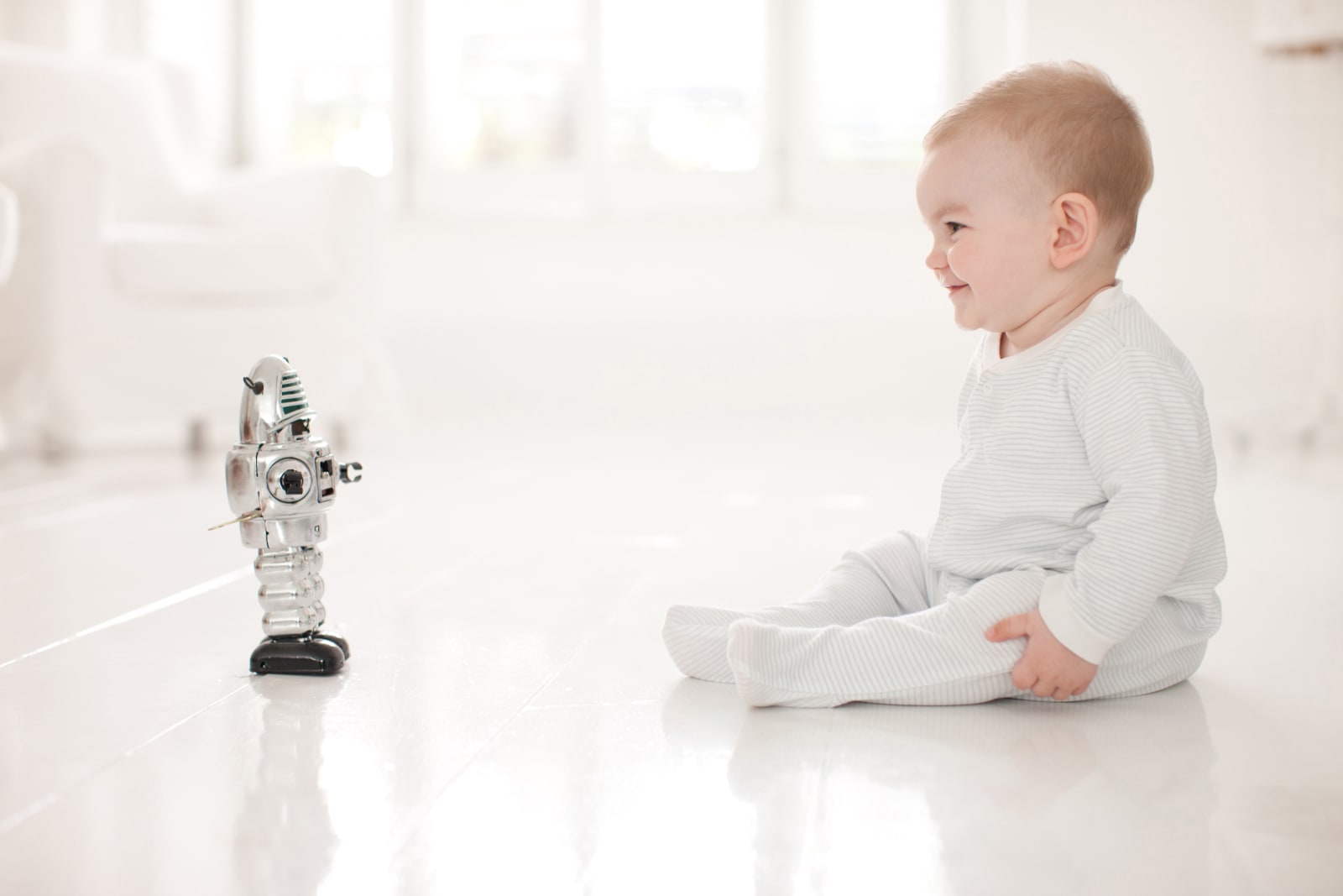 Baby on floor looking at toy robot