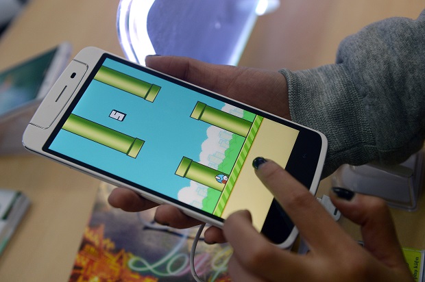 An employee plays the game Flappy Bird at a smartphone store in Hanoi on February 10, 2014.  The Vietnamese developer behind the smash-hit free game Flappy Bird has pulled his creation from online stores after announcing that its runaway success had ruined his 