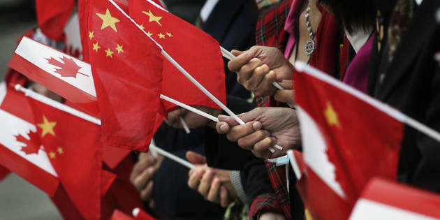 People gather holding Chinese and Canadian flags in Vancouver, B.C.