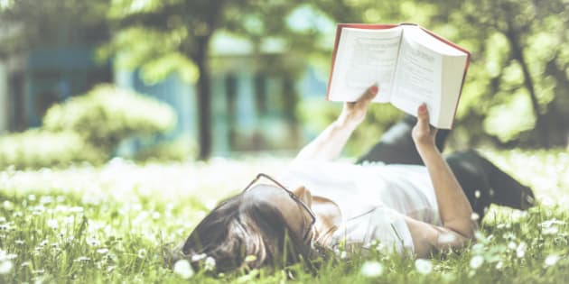 Mid adult woman is reading a book in a garden