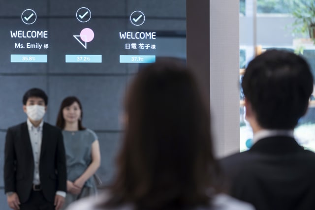 TOKYO, JAPAN - JULY 13: Employees stand in front of a monitor during a demonstration of the portalless, touchless smart entrance that allows temperature checks and facial recognition for masked faces at NEC Corporation headquarters on July 13, 2020 in Tokyo , Japan. NEC Corporation transformed the skyscraper at its Tokyo headquarters into a smart building to display its 