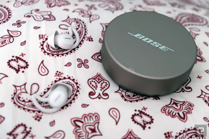 Bose Sleepbuds 2 headphones with their circular case on a patterned tablecloth.
