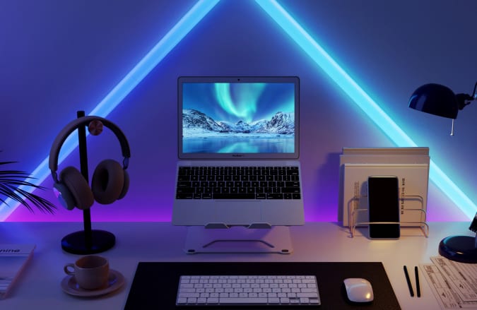 A laptop setup on a desk with neon-like blue Glide wall light by Govee behind it.