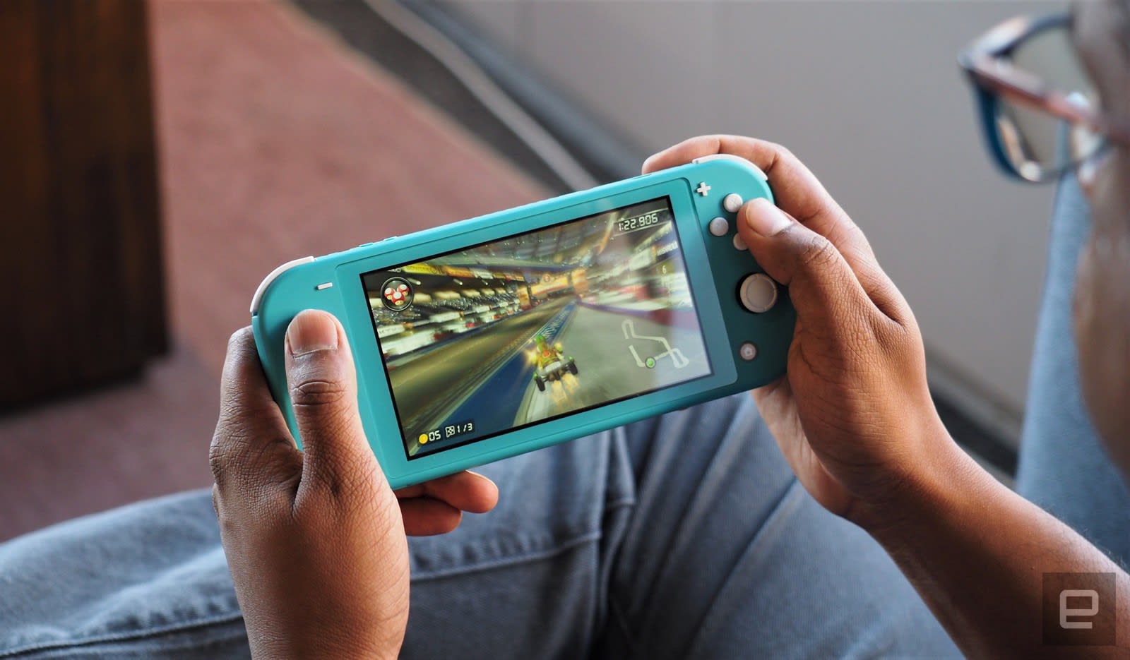 An over-the-shoulder view of someone playing a Nintendo Switch Lite portable gaming device.