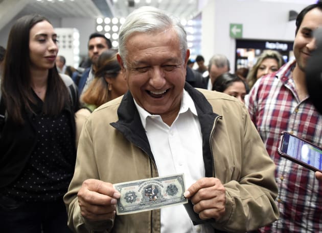 El presidente de México Andrés Lopez Obrador bromea ante periodistas con un billete de cinco