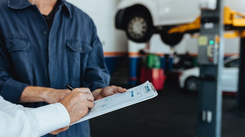 Auto mechanic taking sign on document from customer