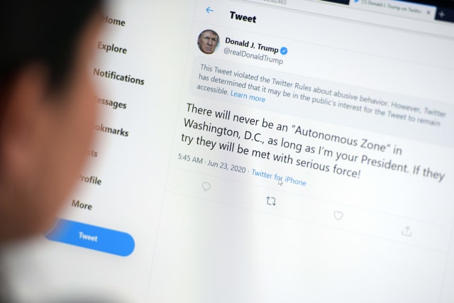 This illustration photo shows a woman in Los Angeles looking at the official Twitter account of US President Donald Trump on June 23, 2020, with a tweet by the president which Twitter considered "abusive" and hid it. - Twitter on Tuesday hid a tweet from President Donald Trump in which he threatened to use "serious force" against protestors in the US capital, saying it broke rules over abusive content. The move appeared to be the first by Twitter against the president for an "abusive" tweet. In a growing dispute, the platform has recently labeled other Trump tweets as misleading and violating its standards on promoting violence. (Photo by - / AFP) (Photo by -/AFP via Getty Images)