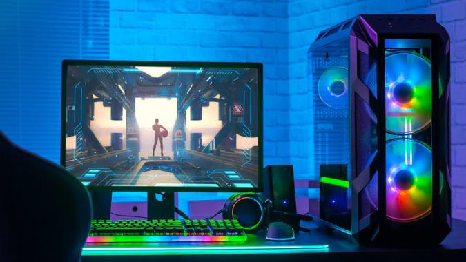 A gaming PC with a platform, monitor, keyboard and mouse, bright and rainbow lighting.