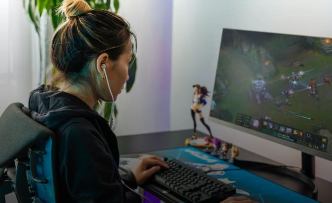 A gamer sits in front of a computer wearing Logitech G333 earbuds.