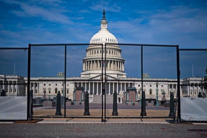 The front of the US Capitol building seen through protective barriers.
