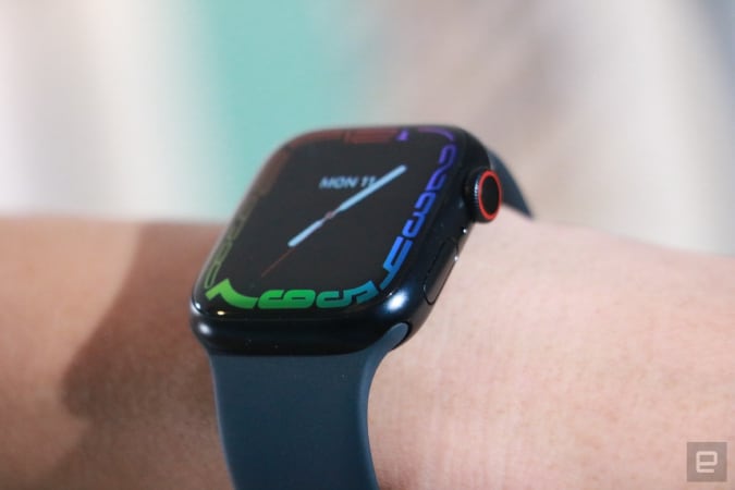 An off-angle view of the Apple Watch Series 7 on a person's pulse, showing the refracted edge of the screen and the dial and button of the watch.