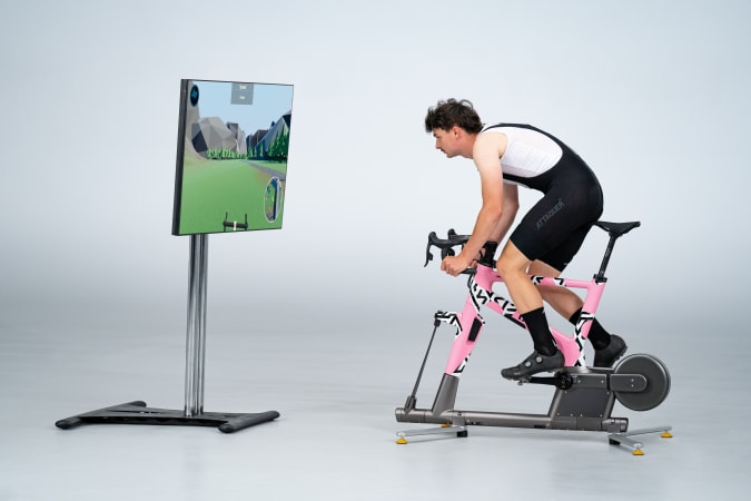 A rider on a Muoverti TiltBike using a virtual training experience that's displayed on a TV.