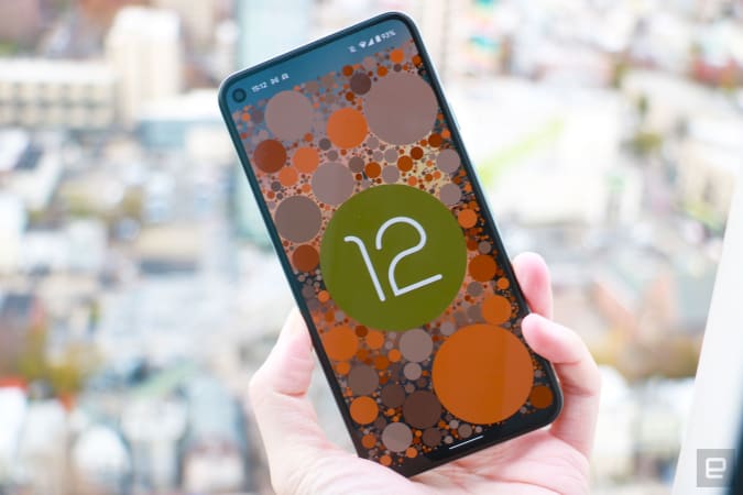 A phone showing the Android 12 easter egg, which is the OS logo on a background of circles themed to the system's color scheme.