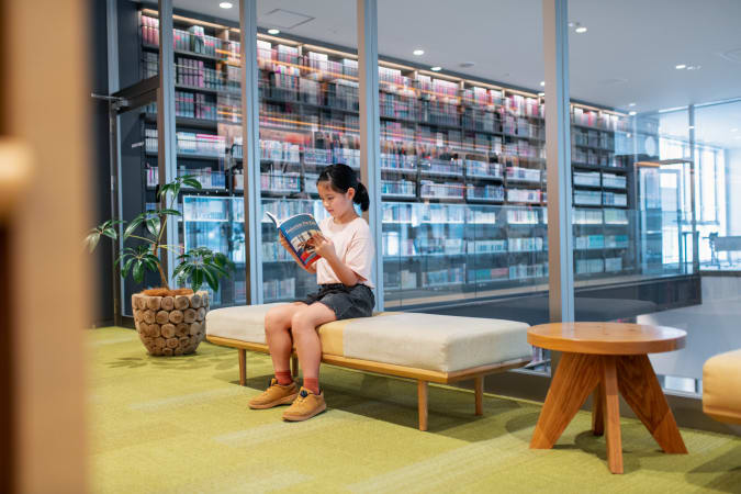 Young girl reading a robotics book in a library. Okayama, Japan
