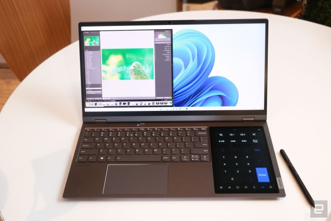 Lenovo ThinkBook Plus Gen 3 nằm trên một chiếc bàn tròn màu trắng với bút stylus bên cạnh.  Máy tính xách tay hiển thị Adobe Lighthouse chiếm nửa bên trái của màn hình chính, trong khi một hạt nhân ngoại cỡ xuất hiện trên màn hình 8 inch ở bên phải bàn phím.