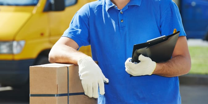 Stock image of a gloved male delivery man holding a clipboard, photographed from the neck down.