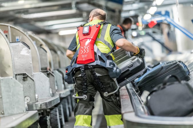 A baggage handler wears a Cray X Exoskeleton from German Bionic while handling a baggage.