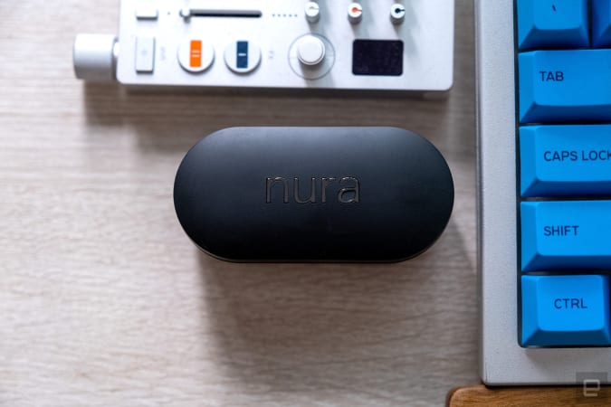 The NuraTrue wireless headphones pictured in their closed charging case.