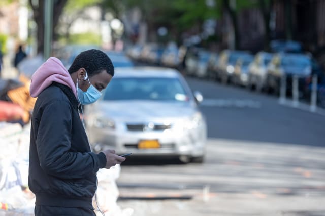 NEW YORK, NEW YORK - APRIL 28: A man wearing a protective mask looks at his iPhone amid the coronavirus pandemic on April 28, 2020 in New York City, New York. COVID-19 has spread to most countries around the world, claiming over 217,000 lives with over 3.1 million cases (Photo by Alexi Rosenfeld/Getty Images)