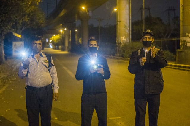 NEW DELHI, INDIA - APRIL 05: Indians hold candles and smartphone flashlights on a deserted main road for nine minutes to show solidarity in the fight against the coronavirus as a nationwide lockdown continues on April 05, 2020 in New Delhi, India. India is under a 21-day lockdown to fight the spread of the virus. After an appeal by Indian Prime Minister Narendra Modi, millions of Indians on Sunday switched off lights in their houses at 9 pm for nine minutes to show solidarity in the country's fight against the coronavirus. The lockdown has already disproportionately hurt marginalized communities due to the loss of livelihood and lack of food, shelter and other basic needs. The lockdown has left tens of thousands of out-of-work migrant workers stranded, with rail and bus services shut down. The closing of state borders has caused disruption in the supply of essential goods, leading to inflation and fear of shortages. There are more than 3,500 positive coronavirus cases in India with currently 99 deaths. (Photo by Yawar Nazir/Getty Images)