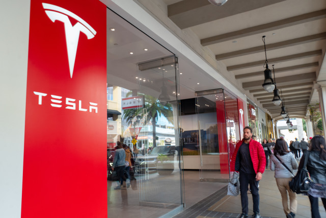 People walk past facade with logo at Tesla Motors store on Santana Row in the Silicon Valley, San Jose, California, December 14, 2019. (Photo by Smith Collection/Gado/Getty Images)
