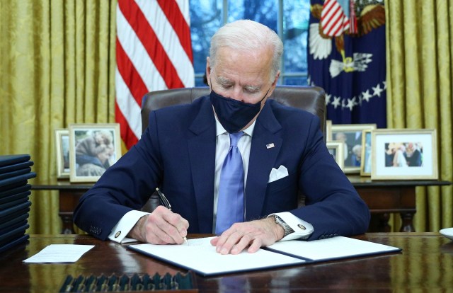 U.S. President Joe Biden signs executive orders in the Oval Office of the White House in Washington, after his inauguration as the 46th President of the United States, U.S., January 20, 2021. REUTERS/Tom Brenner