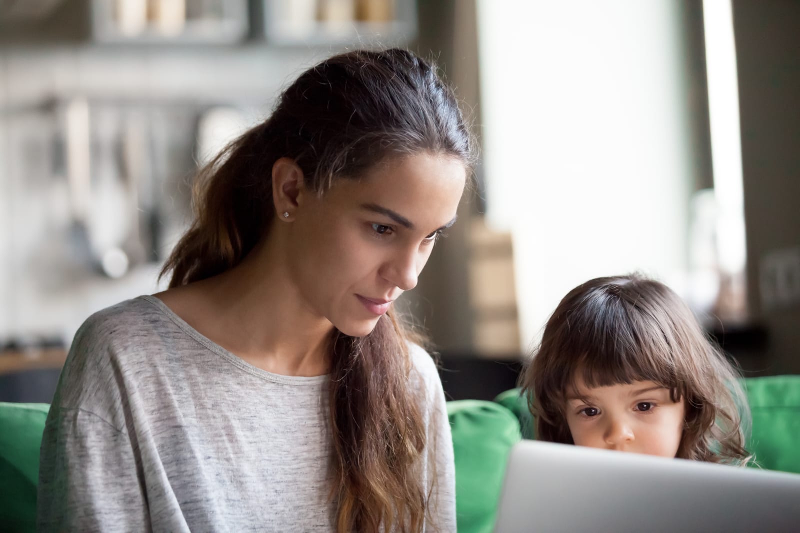 Serious single mother using laptop together with daughter