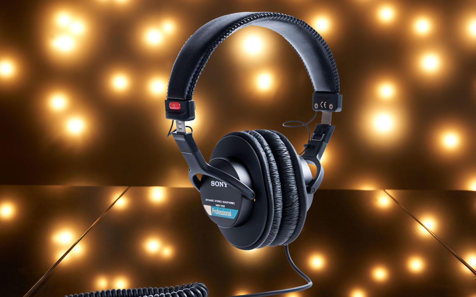 The Sony MDR-7506 headphones suspended in the air in front of a dark background dotted with bright light spots.
